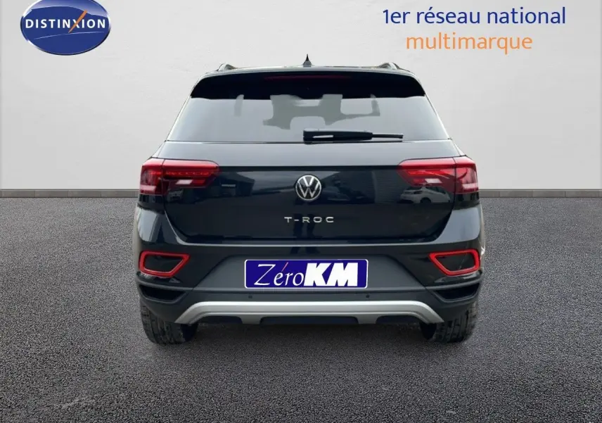 Vue arrière d'un Volkswagen T-Roc noir Grenadilla Metal avec feux arrière allumés et détails rouges sur le pare-chocs.
