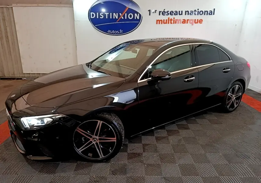 Mercedes Classe A Berline noire vue en 3/4 avant droit, avec jantes alliage et feux LED allumés dans un showroom.
