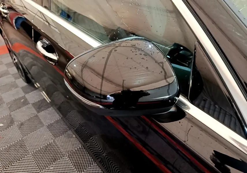 Gros plan sur le rétroviseur côté gauche noir brillant d’une Mercedes Classe A Berline A 200 d Progressive Line 2022.