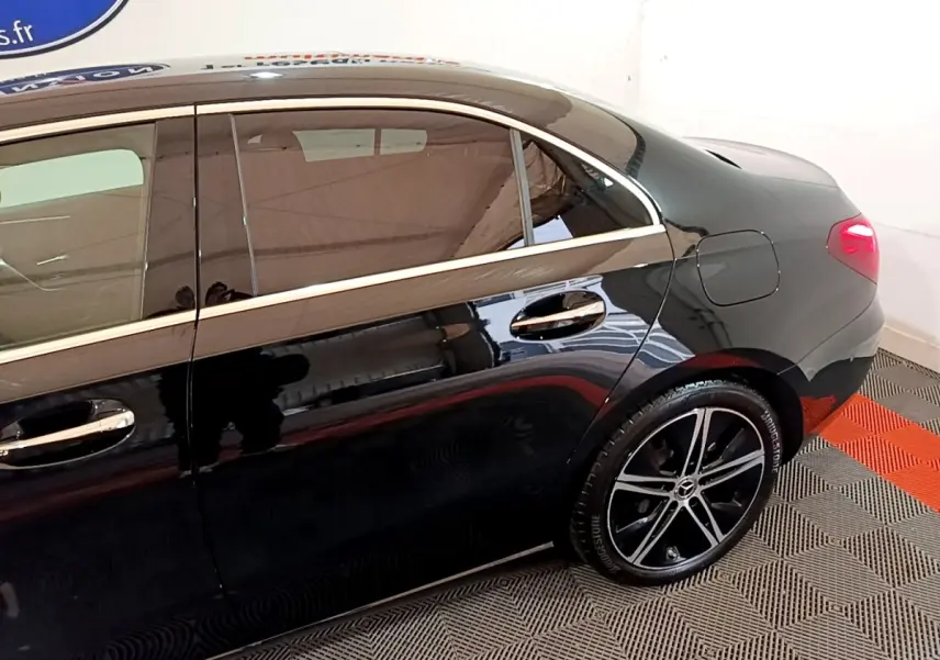 Vue latérale droite d'une Mercedes Classe A Berline noire, mettant en valeur les jantes alliage et les poignées chromées.