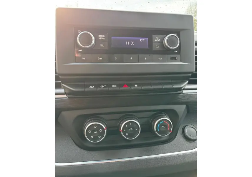 Vue rapprochée du tableau de bord du Renault Trafic Fourgon gris clair, montrant la radio et les commandes de climatisation.