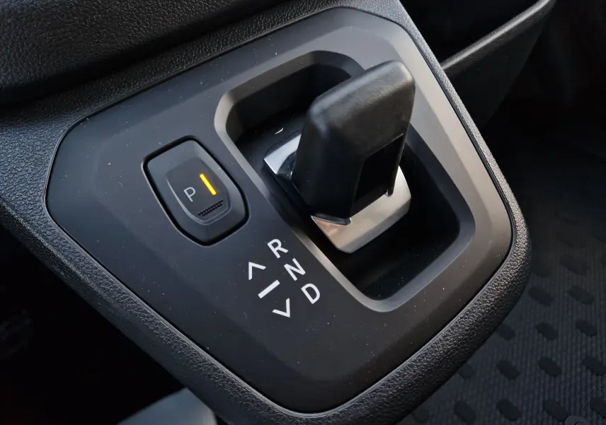 Gros plan sur le levier de vitesses automatique noir du Renault Trafic Fourgon 2025, avec bouton de parking lumineux.