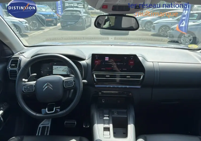 Vue intérieure avant du Citroën C5 Aircross 2023 gris acier, tableau de bord moderne avec écran tactile et volant multifonction.