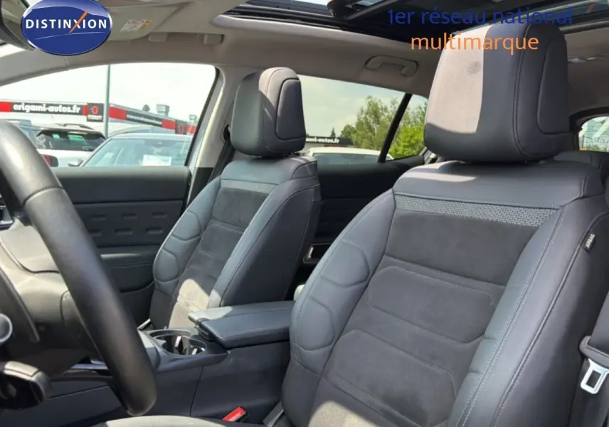 Vue intérieure montrant les sièges avant en tissu et cuir noir du Citroën C5 Aircross 2023, avec accoudoir central.