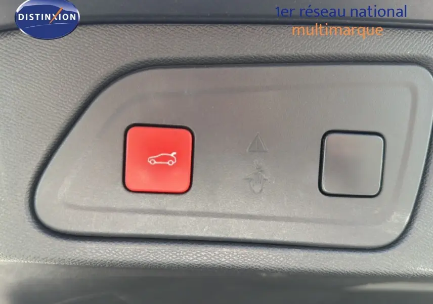 Vue rapprochée du bouton rouge d'ouverture du hayon sur un tableau de bord gris du Citroën C5 Aircross gris acier.