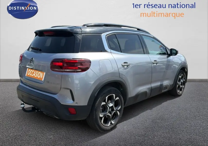 Vue 3/4 arrière droite d'un Citroën C5 Aircross gris acier avec toit noir et jantes bi-ton, stationné sur sol gris.