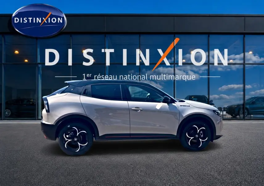 Profil droit de l'Alfa Romeo Junior 1.2 hybride 2026 en ivoire et noir, avec jantes alliage et toit noir contrasté.