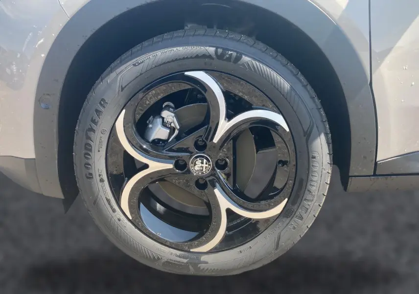 Gros plan sur la jante en alliage noire et ivoire d'une Alfa Romeo Junior 1.2 hybride, côté arrière droit.