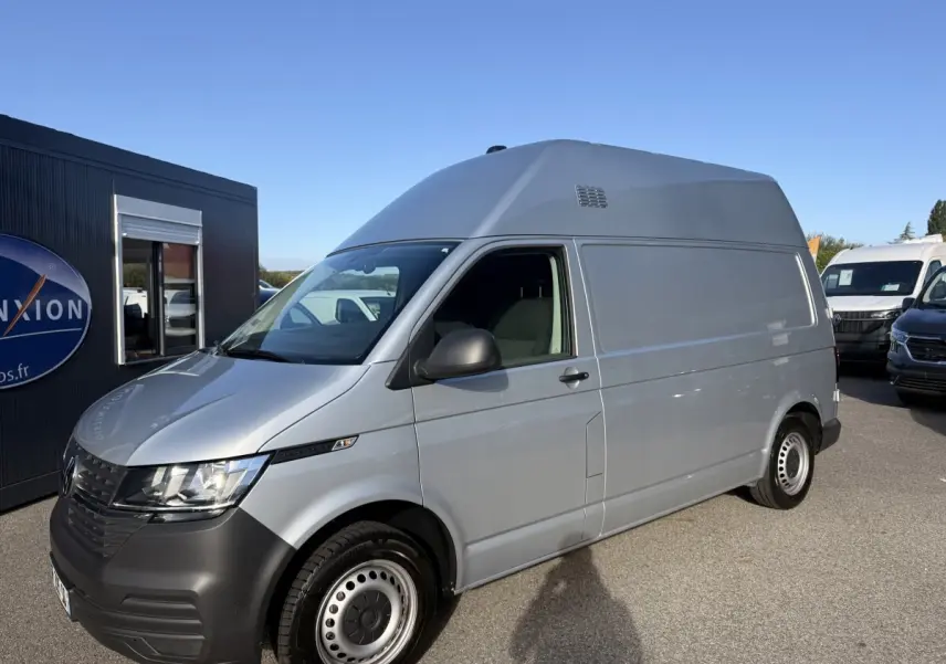 Vue 3/4 avant droit d’un Volkswagen Transporter gris clair version 2.0 TDi 110 L2H1 Business avec jantes acier.