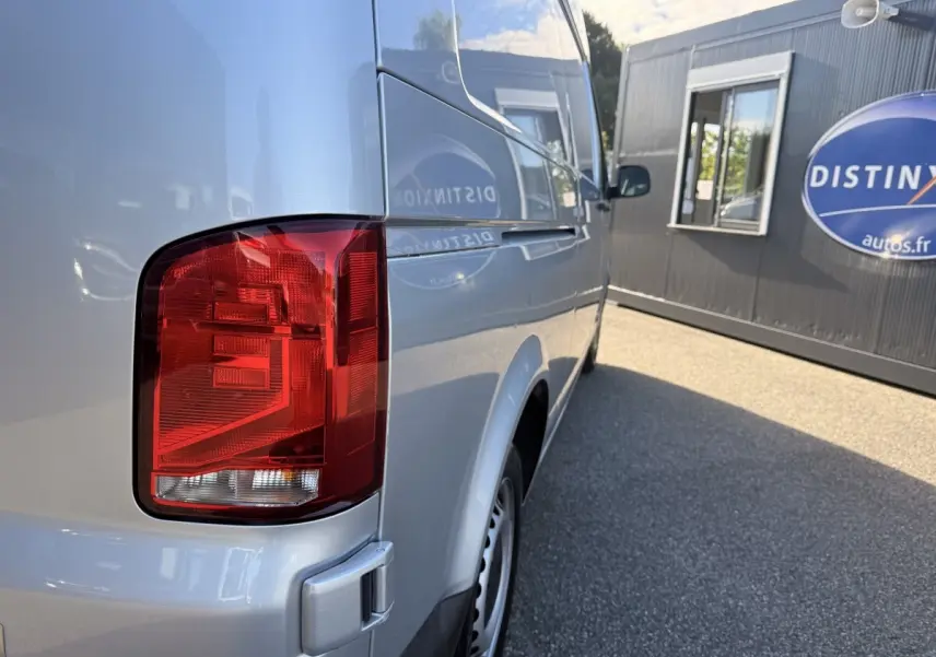 Vue arrière côté droit du Volkswagen Transporter gris clair, mettant en valeur le feu arrière et la carrosserie lisse.