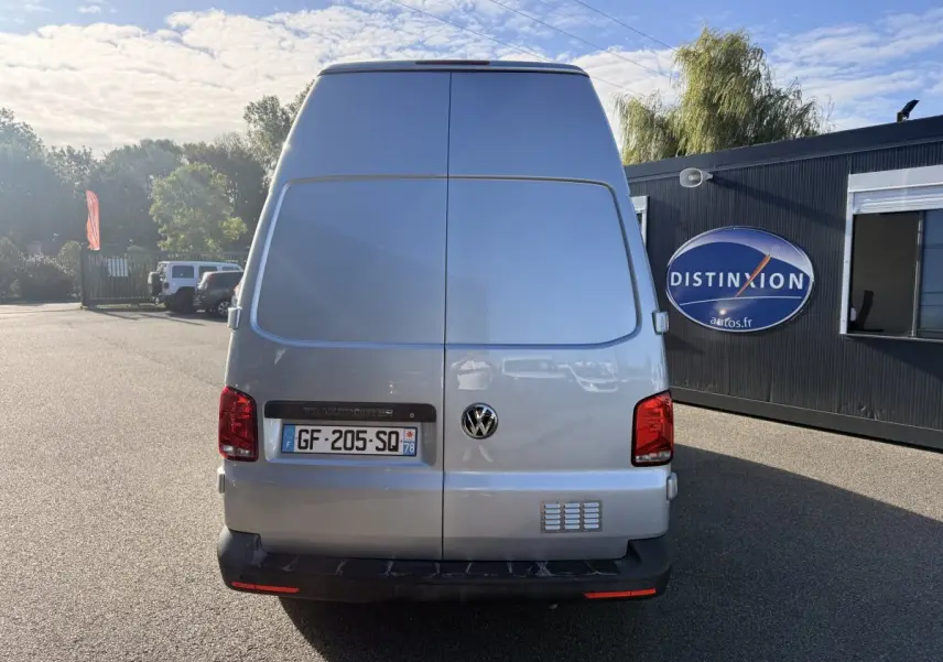 Vue arrière d’un Volkswagen Transporter gris clair 2.0 TDi 110 L2H1 avec portes battantes fermées, stationné en extérieur.