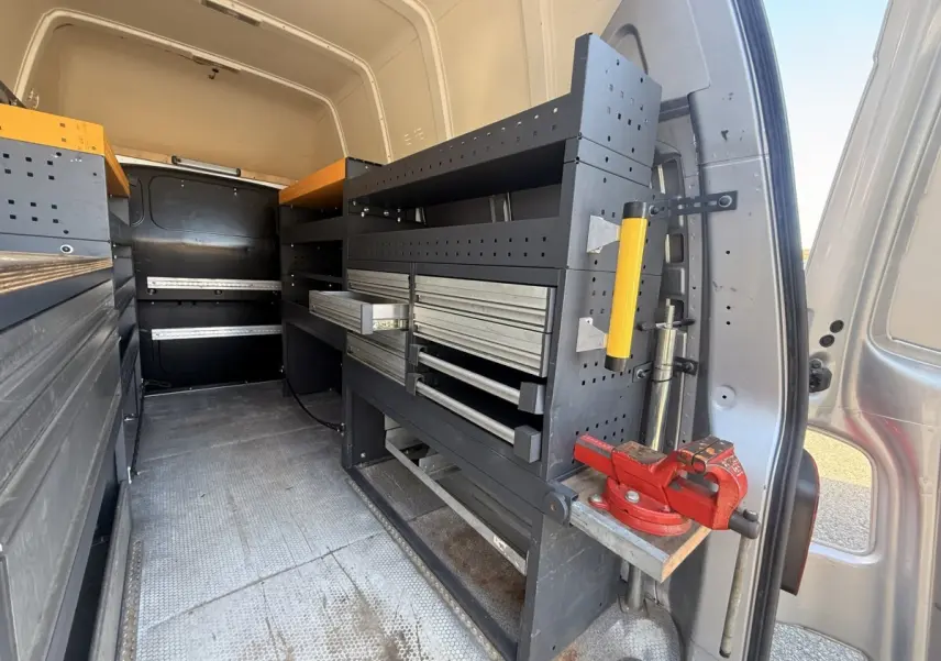 Vue intérieure arrière droite du Volkswagen Transporter gris clair 2022 avec aménagements de rangement et étagères métalliques.