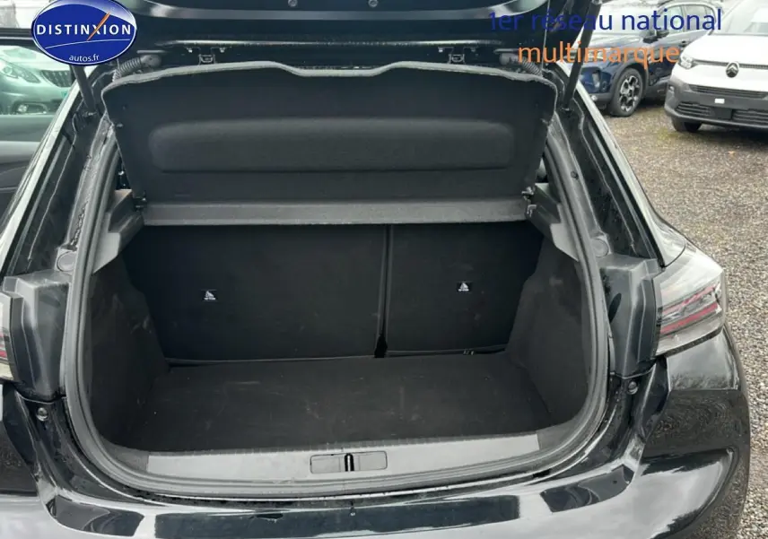 Coffre ouvert vu de l'arrière d'une Peugeot 208 noire, montrant un espace de chargement vide et propre.