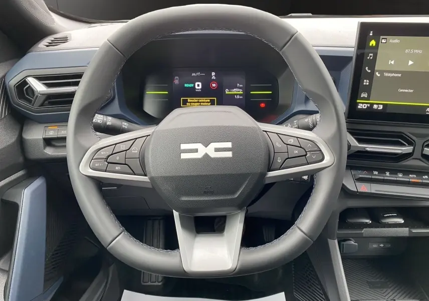 Vue centrée sur le volant et le tableau de bord du Dacia Duster Full Hybrid 140 gris schiste, avec écran tactile et commandes intégrées.