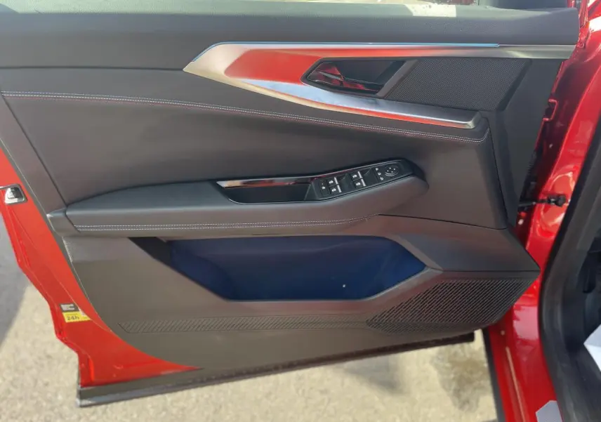 Vue rapprochée de la porte avant gauche rouge du Renault Rafale 2025, avec commandes électriques et surpiqûres blanches.