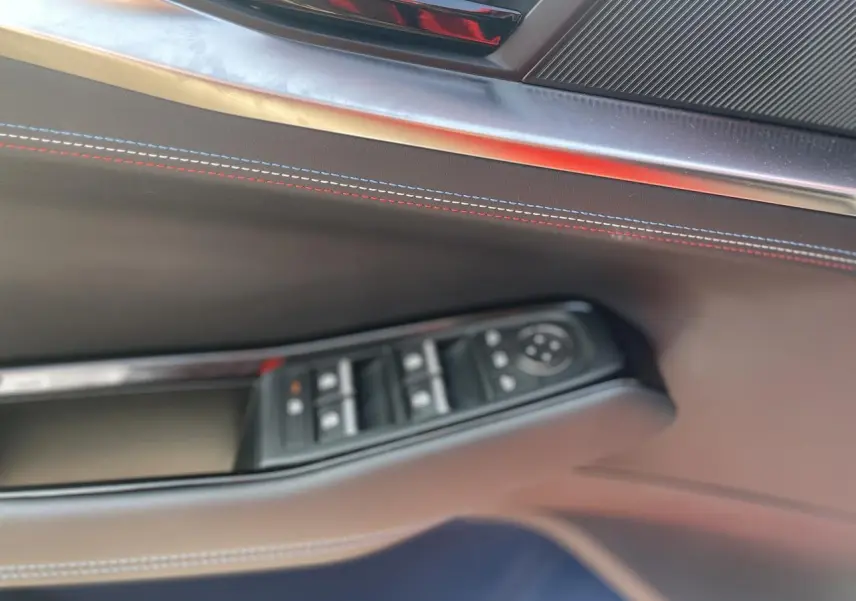 Détail de la porte côté gauche de la Renault Rafale 2025 avec surpiqûres tricolores et commandes de vitres.