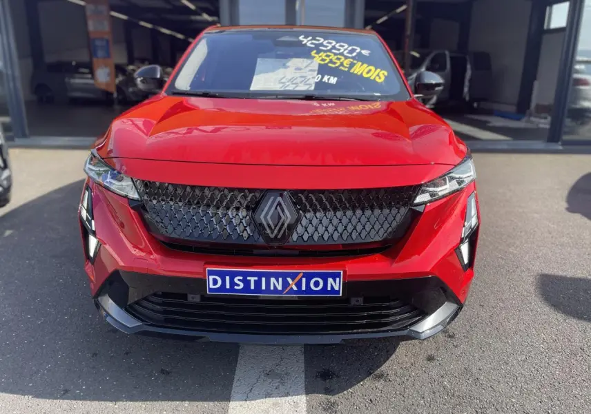 Vue frontale d'une Renault Rafale rouge avec calandre noire et logo distinctif, sur parking extérieur.