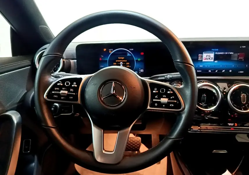 Vue intérieure centrée sur le volant cuir noir et le tableau de bord numérique de la Mercedes CLA 200 d Business Line.