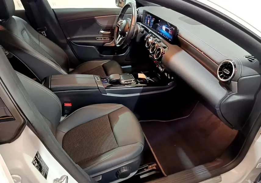 Vue intérieure côté conducteur de la Mercedes CLA 200 d Business Line blanche, tableau de bord digital et sièges noirs.