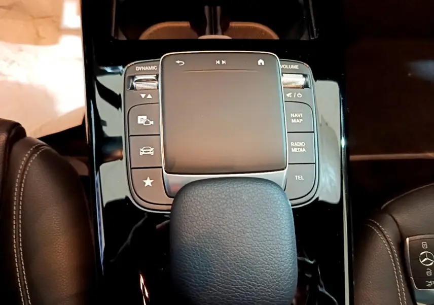 Vue rapprochée du pavé tactile central noir brillant et du levier de vitesse en cuir dans l’habitacle d’une Mercedes CLA 200 d blanche.