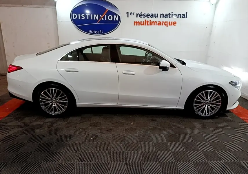 Vue latérale droite d'une Mercedes CLA 200 d Business Line blanche, avec jantes alliage et feux arrière allumés.