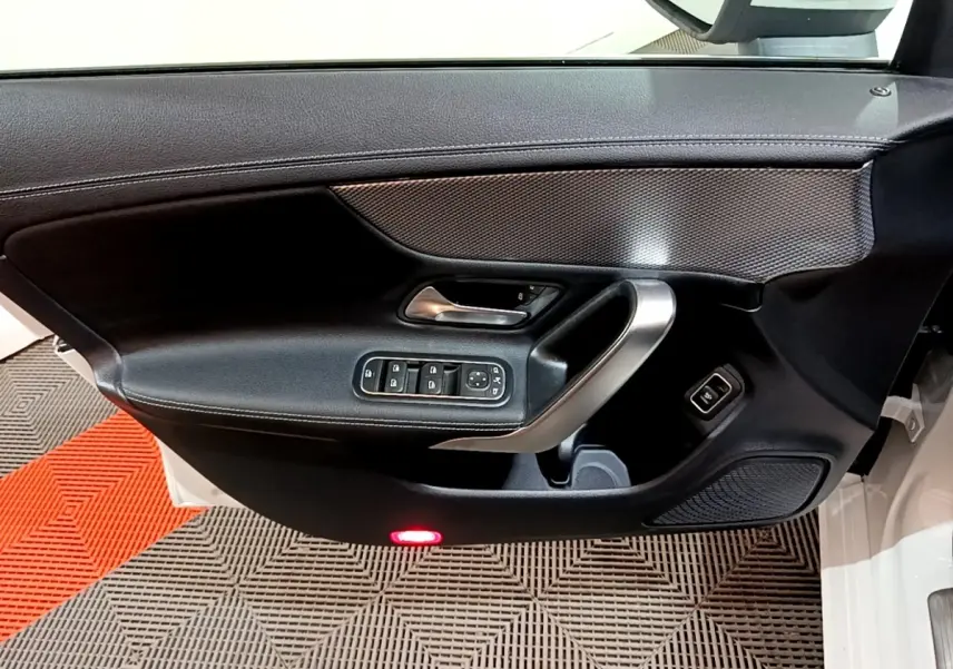 Vue intérieure du panneau de porte avant gauche noir avec commandes électriques sur Mercedes CLA 200 d blanc.