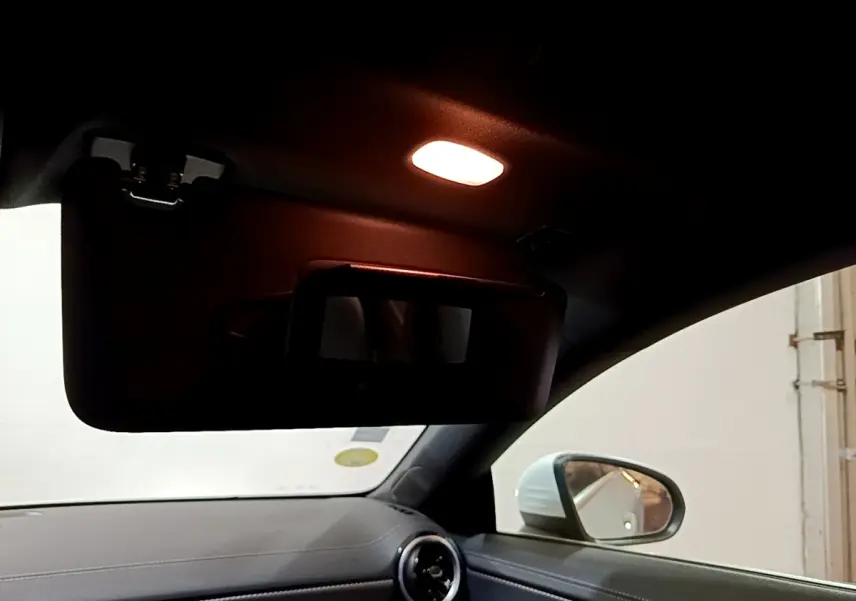 Intérieur de Mercedes CLA 200 d blanc, vue côté droit sur pare-soleil avec miroir éclairé et rétroviseur extérieur.