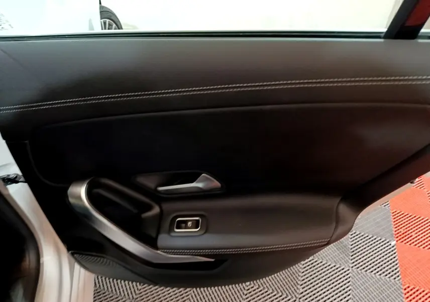 Vue rapprochée du panneau de porte intérieur côté gauche noir avec surpiqûres blanches d'une Mercedes CLA 200 d Business Line blanche.