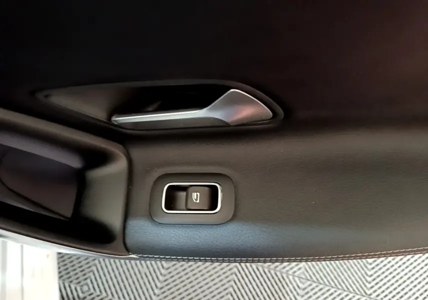 Détail de la poignée intérieure et bouton de verrouillage de porte côté gauche d’une Mercedes CLA 200 d Business Line blanche.