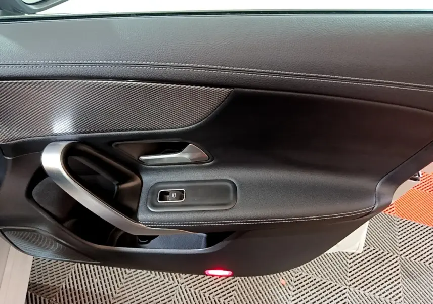 Vue rapprochée de la porte côté gauche noire de la Mercedes CLA 200 d Business Line avec poignée alu et bouton de vitre électrique.