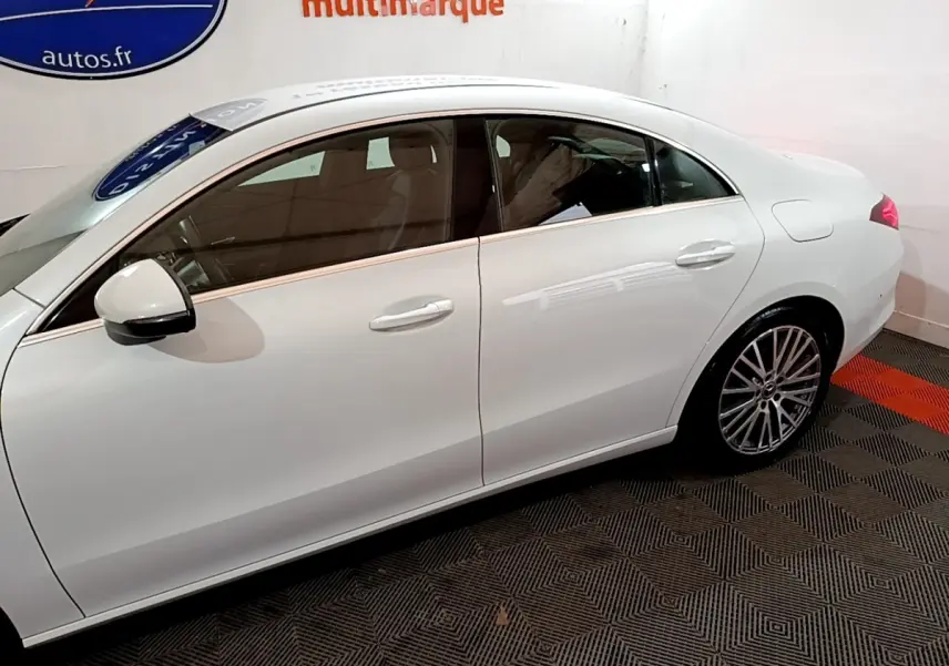 Vue latérale côté gauche d'une Mercedes CLA 200 d Business Line blanche, avec jantes alliage et rétroviseur blanc.