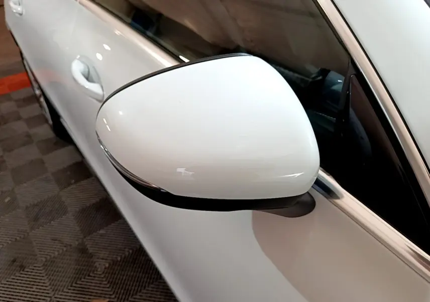 Gros plan sur le rétroviseur droit blanc d’une Mercedes CLA 200 d Business Line 2021, avec porte et vitre partiellement visibles.