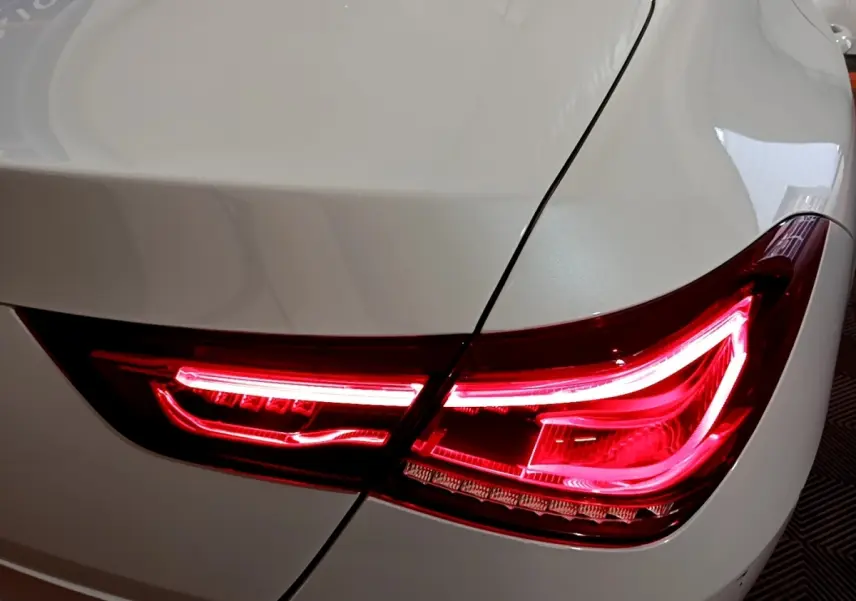 Gros plan sur le feu arrière droit rouge allumé d’une Mercedes CLA 200 d Business Line blanche.