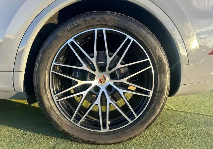 Gros plan sur la roue avant droite du Porsche Cayenne III Coupe 3.0 V6 S e-Hybrid 2024 en gris arctique.