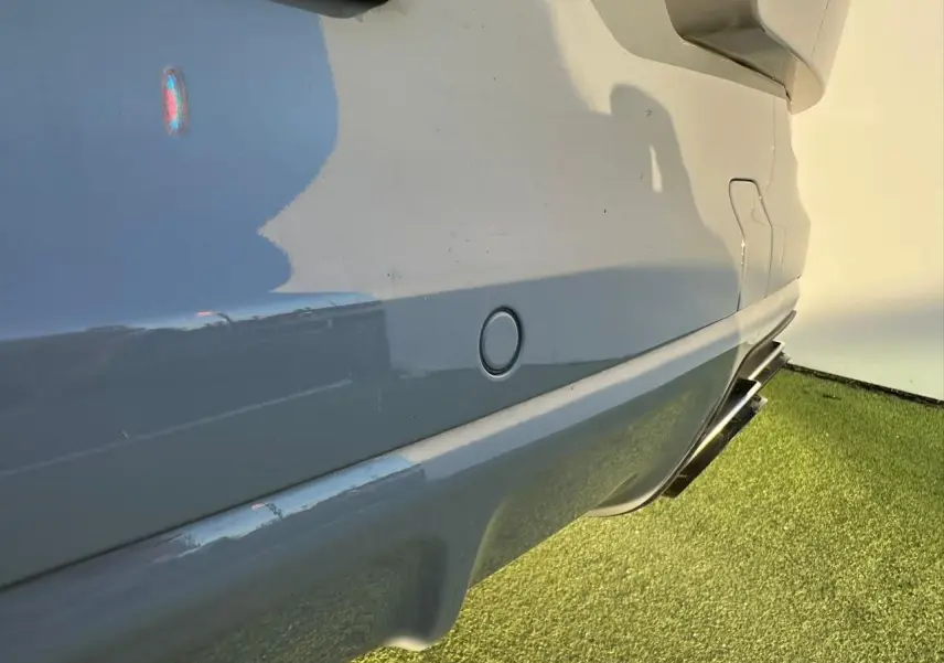 Gros plan sur le côté droit arrière gris arctique du Porsche Cayenne 2024, avec sortie d’échappement double visible.