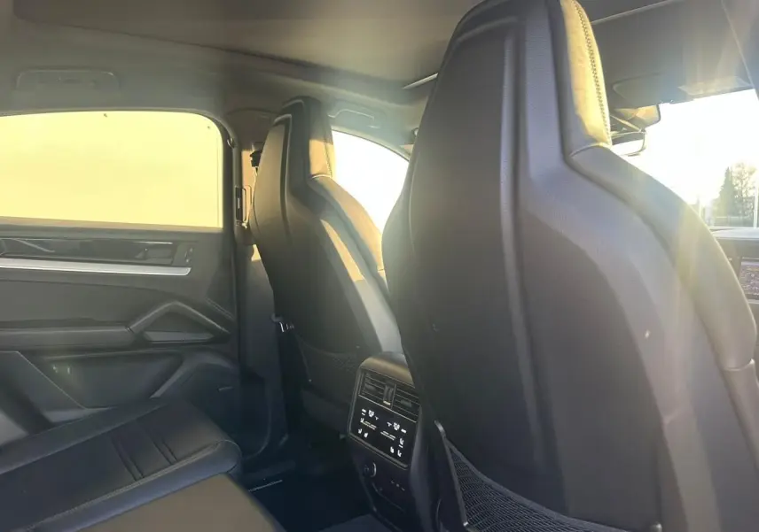 Vue intérieure arrière du Porsche Cayenne III Coupe 3.0 V6 S E-Hybrid 2024, montrant les sièges noirs et la console centrale arrière.