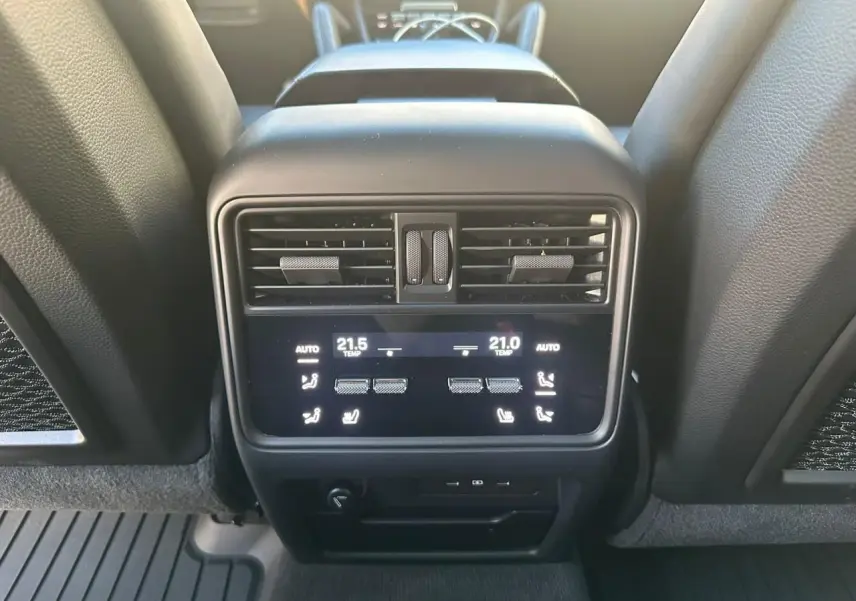 Détail de la console arrière du Porsche Cayenne 2024 en gris arctique, montrant les commandes de climatisation et les aérateurs.