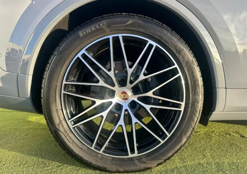 Gros plan sur la roue avant droite du Porsche Cayenne 2024 gris arctique, avec jante alliage noire et argentée distinctive.