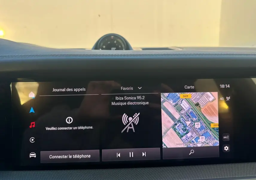 Vue rapprochée de l'écran tactile central du Porsche Cayenne 2024 gris arctique, affichant navigation et musique.