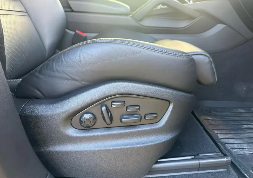 Gros plan sur les commandes électriques du siège conducteur en cuir noir d’un Porsche Cayenne 2024.