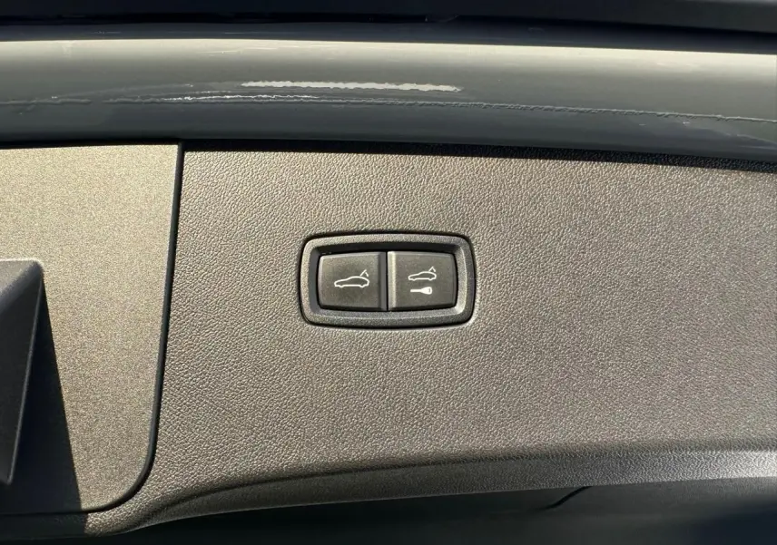 Gros plan sur les boutons d'ouverture du coffre et du hayon du Porsche Cayenne Coupé 2024 en gris arctique.