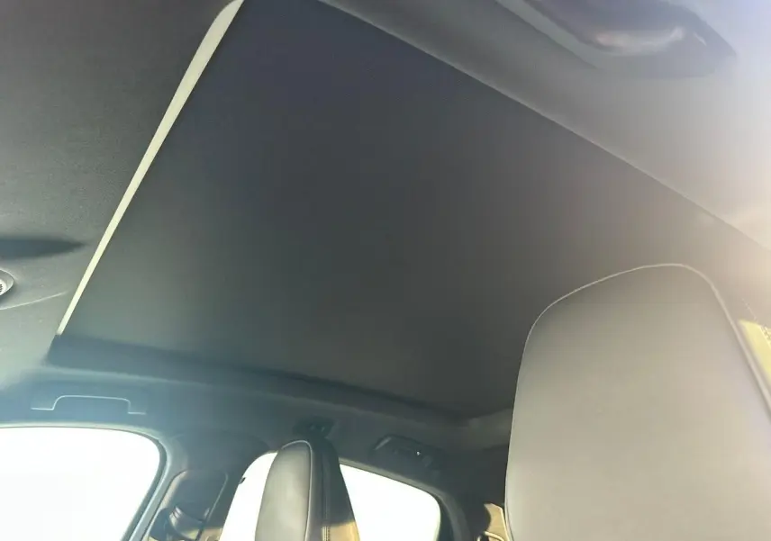 Vue intérieure du toit ouvrant fermé et des appuie-têtes avant du Porsche Cayenne III Coupe gris arctique 2024.