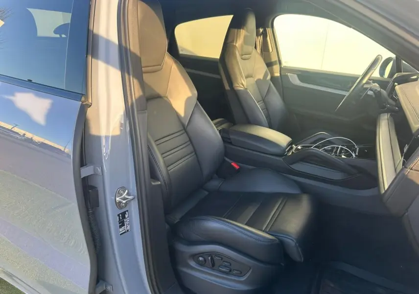 Vue intérieure côté conducteur du Porsche Cayenne 2024 gris arctique, mettant en valeur les sièges en cuir noir et la console centrale.