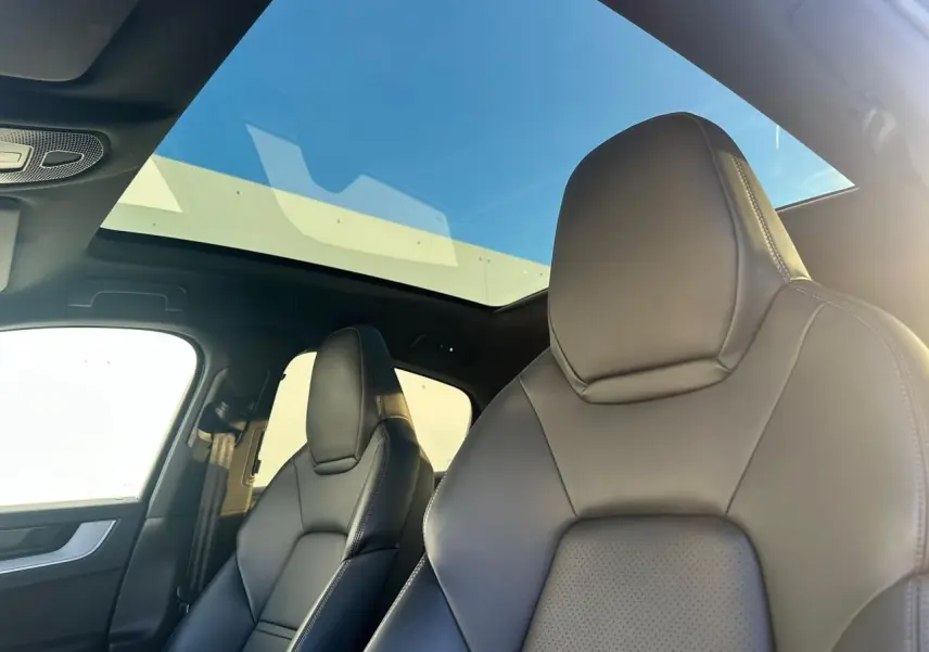 Vue intérieure sur les sièges avant en cuir noir du Porsche Cayenne 2024 avec toit panoramique et lumière naturelle.