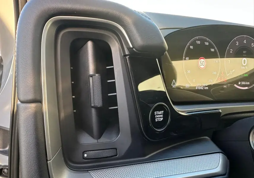 Détail intérieur du tableau de bord côté gauche du Porsche Cayenne 2024, avec bouton Start Engine Stop et écran digital.