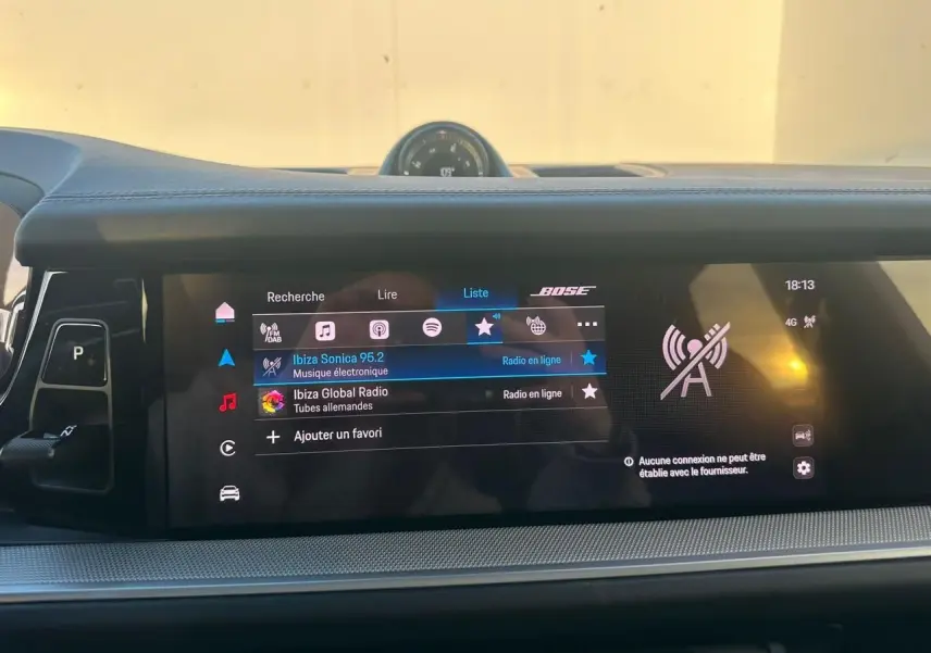 Vue intérieure du tableau de bord du Porsche Cayenne III Coupe 3.0 V6 S E-Hybrid 2024, écran tactile avec interface audio et horloge centrale.