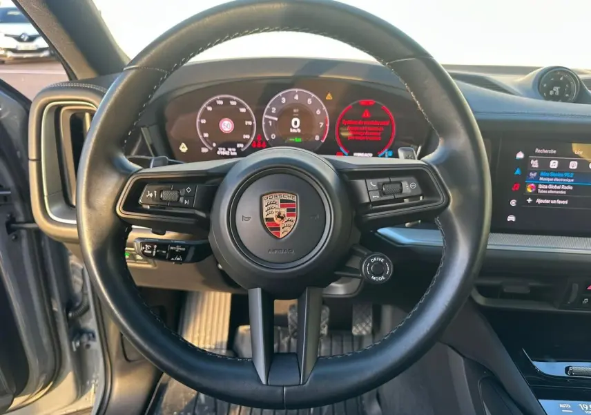Vue intérieure centrée sur le volant noir du Porsche Cayenne 2024 avec tableau de bord numérique et écran tactile.