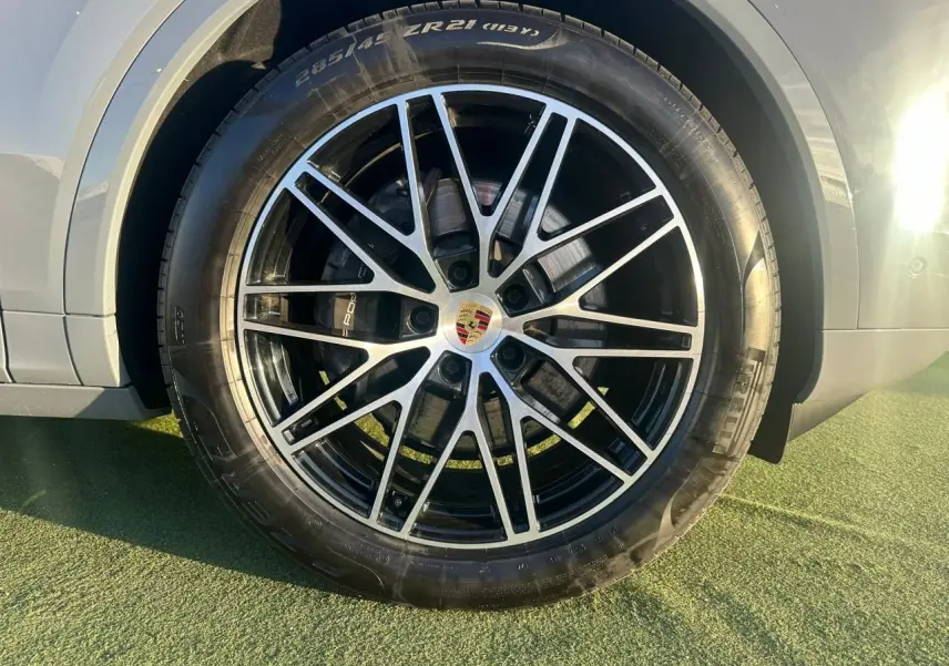 Gros plan sur la roue avant droite du Porsche Cayenne 2024 gris arctique, mettant en valeur la jante alliage noire et argentée.