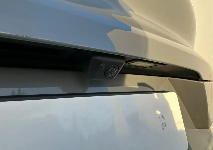 Gros plan sur la caméra de recul intégrée au pare-chocs arrière du Porsche Cayenne Coupé gris arctique 2024.