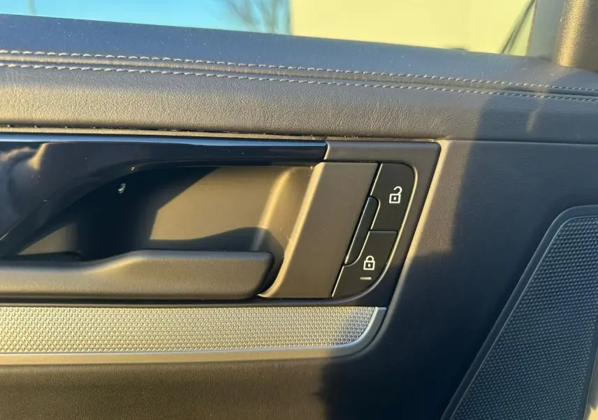 Détail de la poignée intérieure côté gauche de la porte d’un Porsche Cayenne 2024 gris arctique, avec commandes de verrouillage.
